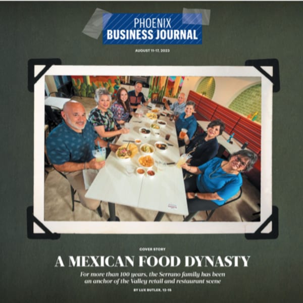 A large family group enjoys a meal together at a long table inside Serrano's Mexican restaurant.