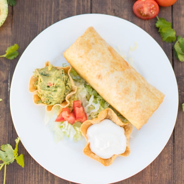 Serrano's Mexican Food Restaurants' golden-brown chimichanga with guacamole, sour cream, and fresh vegetables.